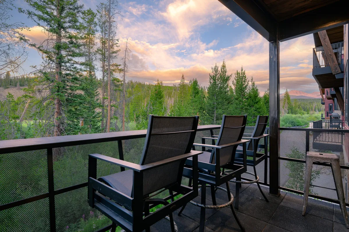 A peaceful exterior balcony scene with comfortable seating, distant trees, and a sweeping mountain view. The setting suggests relaxation and connection with nature, ideal for enjoying sunsets, wildlife sightings, or quiet moments overlooking the river.