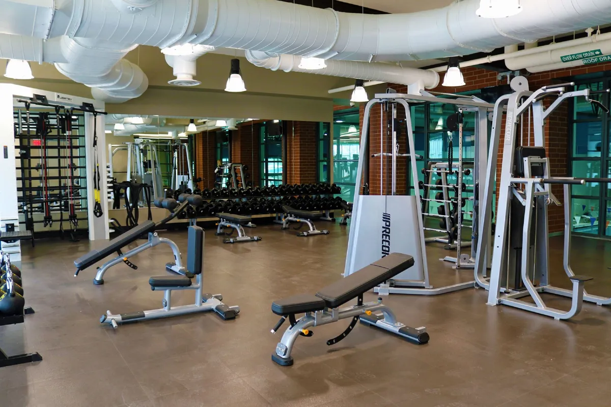 A motivating interior scene of a fitness area with weight benches, a dumbbell rack, and exercise machines. The space is energetic and well-equipped, inviting guests to pursue fitness goals or join group activities.
