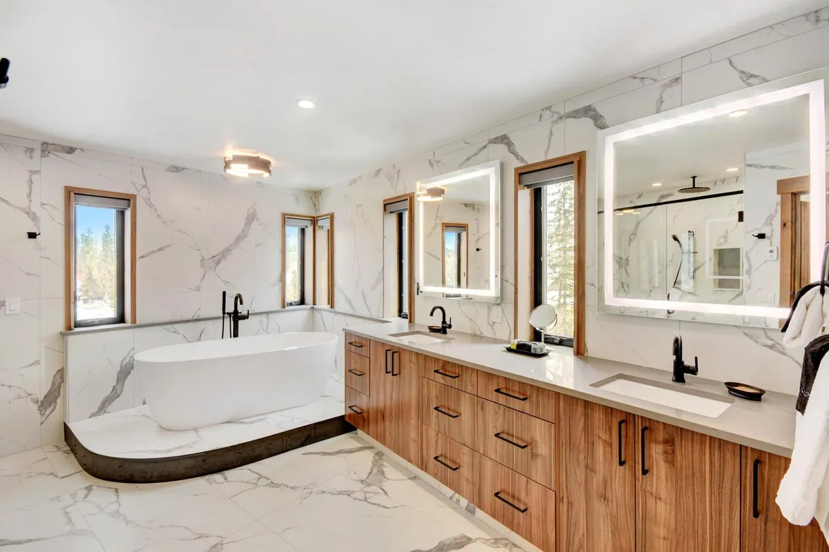 A modern, spa-like bathroom with a freestanding bathtub, dual vanities, expansive windows, and mirrored cabinets. Gentle natural light creates a soothing, sophisticated retreat.