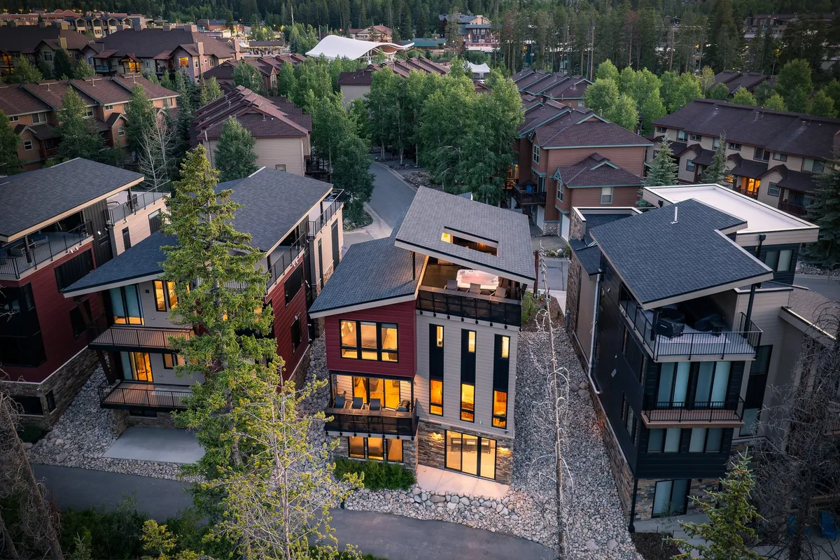 A welcoming exterior showcasing modern architecture framed by a tree line, neighboring houses, and a pathway, setting the scene for community gatherings and outdoor relaxation. The image captures the balance between natural beauty and neighborhood amenities.
